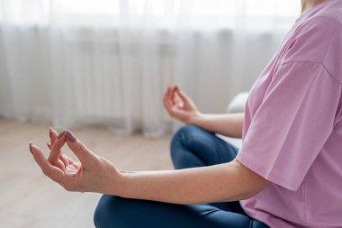 Son sınıf öğrencisi kadın bağdaş kurup yoga minderinde meditasyon yapıyor. Sakinlik ve rahatlığı kucaklıyor..