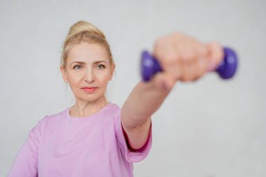 Bir kadın laptopun rehberliğinde ev antrenmanı yapıyor, kapalı bir ortamda yoga minderinin üzerinde geriniyor.