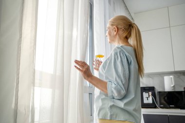 Sebzelerle, içme suyuyla masada oturan ve modern mutfakta ferahlatıcı bir yemeğin tadını çıkaran bir kadın..