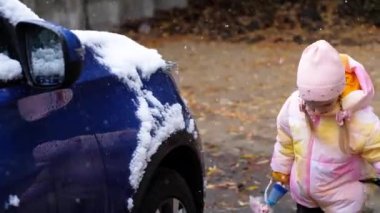 Küçük çocuk sert kış boyunca arabalardaki karı fırçalıyor ve temizliyor..