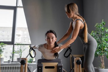 Gösterişli bir spor salonu ortamında kişiselleştirilmiş rehberlik içeren yüksek odaklı bir pilates eğitim oturumunu tecrübe edin.