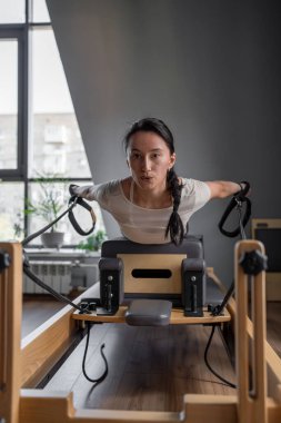 Yoğun bir pilates seansı, bir eğitmenin öğrenciye yenilikçi teçhizat kullanarak ustalıkla rehberlik etmesiyle gerçekleşir.