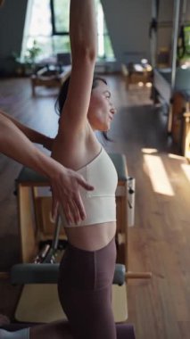 Yetenekli bir pilates eğitmeni, müşteriyi yatıştırıcı bir stüdyoda esneme egzersizinde dikkatlice yönlendirir.