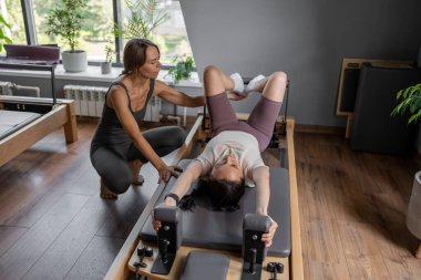 Yetenekli bir pilates eğitmeni, müşteriyi yatıştırıcı bir stüdyoda esneme egzersizinde dikkatlice yönlendirir.