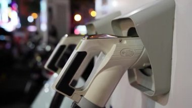 Geceleri çalışan bir elektrikli araç şarj istasyonu, sayısız motosiklet sıraya dizilmiş ve şarj edilmeyi bekliyor.