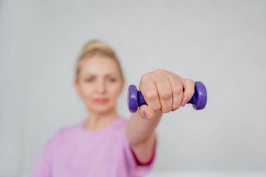 Bir kadın laptopun rehberliğinde ev antrenmanı yapıyor, kapalı bir ortamda yoga minderinin üzerinde geriniyor.