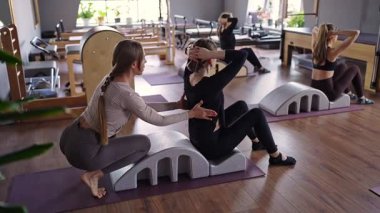 Omurga düzelticisi üzerinde egzersiz yapan bir grup kadın. Beden eğitimi için pilates stüdyosu makinesi. Formda, sağlıklı ve güçlü özgün bir vücut. Fitness konsepti
