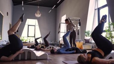 Omurga düzelticisi üzerinde egzersiz yapan bir grup kadın. Beden eğitimi için pilates stüdyosu makinesi. Formda, sağlıklı ve güçlü özgün bir vücut. Fitness konsepti