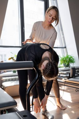 Genç beyaz kadın pilates salonunun parlak stüdyosunda egzersiz yapıyor. Onların çalışmaları modern bir fitness ortamında çekirdek kuvveti ve esnekliği üzerine odaklanır.
