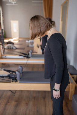 Genç beyaz kadın pilates salonunun parlak stüdyosunda egzersiz yapıyor. Onların çalışmaları modern bir fitness ortamında çekirdek kuvveti ve esnekliği üzerine odaklanır.
