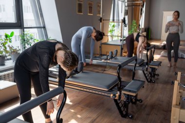 Genç beyaz kadın pilates salonunun parlak stüdyosunda egzersiz yapıyor. Onların çalışmaları modern bir fitness ortamında çekirdek kuvveti ve esnekliği üzerine odaklanır.