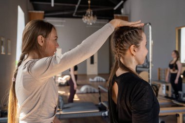 Genç beyaz kadın pilates salonunun parlak stüdyosunda egzersiz yapıyor. Onların çalışmaları modern bir fitness ortamında çekirdek kuvveti ve esnekliği üzerine odaklanır.