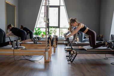 Kadın, ıslah yatağında pilates eğitiyor. Beden eğitimi için pilates stüdyosu makinesi. Formda, sağlıklı ve güçlü özgün bir vücut. Fitness konsepti