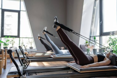 Dengeli Vücut Reformcusu makinesinin güneş ışığıyla aydınlatılan ayak ve çekirdek egzersizinin detaylı bir yakın çekimi. Yüksek kalite fotoğraf