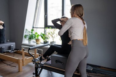 Kadın, göğüs ve sırt kasları için Pilates Reformcusu üzerinde rotasyon egzersizi yapıyor. Kararlılıkla esneklik, güç ve kontrole odaklanıyor..