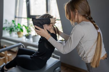 Kadın, göğüs ve sırt kasları için Pilates Reformcusu üzerinde rotasyon egzersizi yapıyor. Kararlılıkla esneklik, güç ve kontrole odaklanıyor..