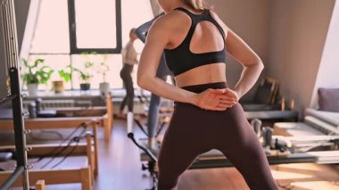 Genç beyaz kadınlar parlak bir stüdyoda pilates reformcuları üzerinde egzersiz yapıyorlar. Onların çalışmaları modern bir fitness ortamında çekirdek kuvveti ve esnekliği üzerine odaklanır..