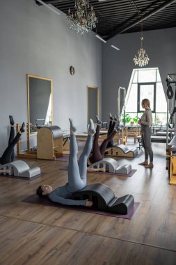 Omurga düzelticisi üzerinde egzersiz yapan bir grup kadın. Beden eğitimi için pilates stüdyosu makinesi. Formda, sağlıklı ve güçlü özgün bir vücut. Fitness konsepti