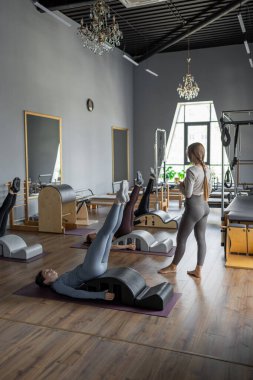 Omurga düzelticisi üzerinde egzersiz yapan bir grup kadın. Beden eğitimi için pilates stüdyosu makinesi. Formda, sağlıklı ve güçlü özgün bir vücut. Fitness konsepti