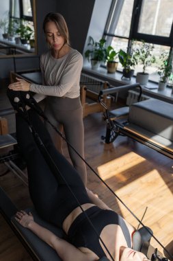 Genç atletik çekici kadın yoga egzersizleri yapıyor, poz veriyor, spor kıyafetleri giyiyor, pantolon ve bluz giyiyor, pilates ve yoga stüdyosu. Sakin, sağlıklı, genç bir bayan nefes alıyor ve yoga yapıyor..