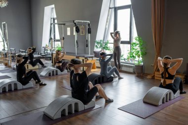 Omurga düzelticisi üzerinde egzersiz yapan bir grup kadın. Beden eğitimi için pilates stüdyosu makinesi. Formda, sağlıklı ve güçlü özgün bir vücut. Fitness konsepti