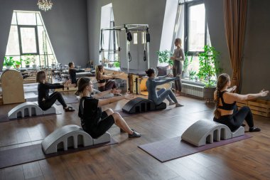 Omurga düzelticisi üzerinde egzersiz yapan bir grup kadın. Beden eğitimi için pilates stüdyosu makinesi. Formda, sağlıklı ve güçlü özgün bir vücut. Fitness konsepti