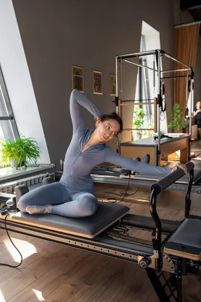 Güneş ışığı, modern pilates stüdyosunda deniz kızı egzersizi yapan kadın sakin, odaklanmış ve güçlü.