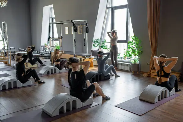 Omurga düzelticisi üzerinde egzersiz yapan bir grup kadın. Beden eğitimi için pilates stüdyosu makinesi. Formda, sağlıklı ve güçlü özgün bir vücut. Fitness konsepti