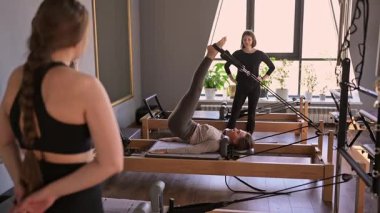 Kadın, ıslah yatağında pilates eğitiyor. Beden eğitimi için pilates stüdyosu makinesi. Formda, sağlıklı ve güçlü özgün bir vücut. Fitness konsepti