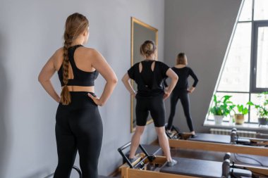 Genç beyaz kadınlar parlak bir stüdyoda pilates reformcuları üzerinde egzersiz yapıyorlar. Onların çalışmaları modern bir fitness ortamında çekirdek kuvveti ve esnekliği üzerine odaklanır..