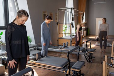Genç beyaz kadın pilates salonunun parlak stüdyosunda egzersiz yapıyor. Onların çalışmaları modern bir fitness ortamında çekirdek kuvveti ve esnekliği üzerine odaklanır.