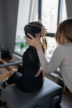 Kadın, göğüs ve sırt kasları için Pilates Reformcusu üzerinde rotasyon egzersizi yapıyor. Kararlılıkla esneklik, güç ve kontrole odaklanıyor..