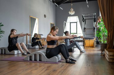 Omurga düzelticisi üzerinde egzersiz yapan bir grup kadın. Beden eğitimi için pilates stüdyosu makinesi. Formda, sağlıklı ve güçlü özgün bir vücut. Fitness konsepti