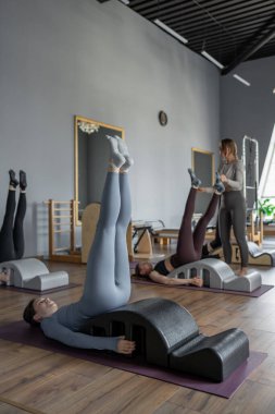 Omurga düzelticisi üzerinde egzersiz yapan bir grup kadın. Beden eğitimi için pilates stüdyosu makinesi. Formda, sağlıklı ve güçlü özgün bir vücut. Fitness konsepti