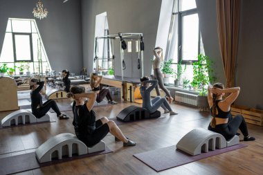Omurga düzelticisi üzerinde egzersiz yapan bir grup kadın. Beden eğitimi için pilates stüdyosu makinesi. Formda, sağlıklı ve güçlü özgün bir vücut. Fitness konsepti