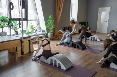 Omurga düzelticisi üzerinde denizkızı egzersizi yapan bir kadın. Beden eğitimi için pilates stüdyosu makinesi. Formda, sağlıklı ve güçlü özgün bir vücut. Fitness konsepti