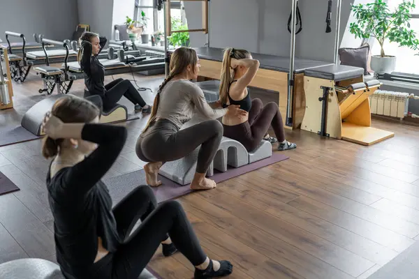 Omurga düzelticisi üzerinde egzersiz yapan bir grup kadın. Beden eğitimi için pilates stüdyosu makinesi. Formda, sağlıklı ve güçlü özgün bir vücut. Fitness konsepti