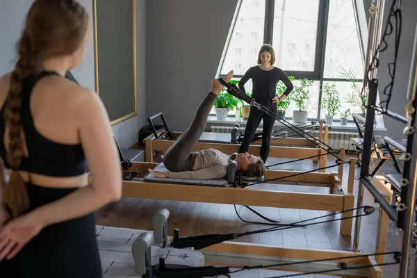 Kadın, ıslah yatağında pilates eğitiyor. Beden eğitimi için pilates stüdyosu makinesi. Formda, sağlıklı ve güçlü özgün bir vücut. Fitness konsepti