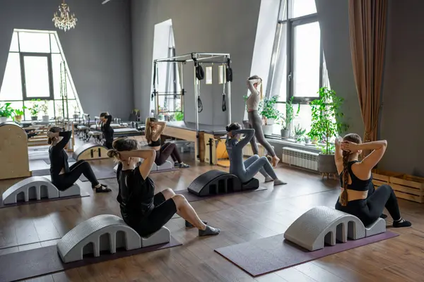 Omurga düzelticisi üzerinde egzersiz yapan bir grup kadın. Beden eğitimi için pilates stüdyosu makinesi. Formda, sağlıklı ve güçlü özgün bir vücut. Fitness konsepti
