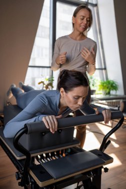 Göğüs ve sırt kasları için Kuğu egzersizi yapan kadın, esneklik, güç ve kararlılıkla kontrol üzerine odaklanıyor.