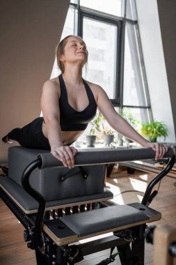 Kadın, ıslah yatağında pilates eğitiyor. Beden eğitimi için pilates stüdyosu makinesi. Formda, sağlıklı ve güçlü özgün bir vücut. Fitness konsepti