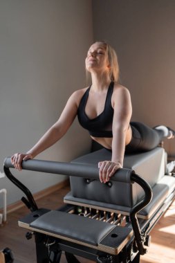 Kadın, ıslah yatağında pilates eğitiyor. Beden eğitimi için pilates stüdyosu makinesi. Formda, sağlıklı ve güçlü özgün bir vücut. Fitness konsepti