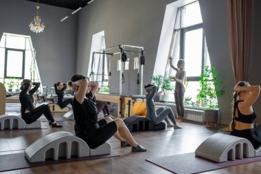 Omurga düzelticisi üzerinde egzersiz yapan bir grup kadın. Beden eğitimi için pilates stüdyosu makinesi. Formda, sağlıklı ve güçlü özgün bir vücut. Fitness konsepti