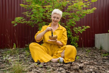 Sakin bir açık hava ortamında, dikkat çekmek için bir şarkı kasesi kullanarak sakin bir meditasyon pratiği yapın.