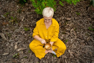 Sakin bir açık hava ortamında, dikkat çekmek için bir şarkı kasesi kullanarak sakin bir meditasyon pratiği yapın.