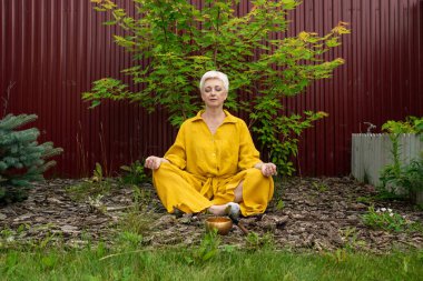 Huzurlu ve sakin bir meditasyon sahnesi. Sarılı, yemyeşil giyinmiş bir kadın.