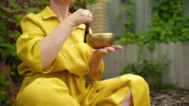 Açık havada huzurlu bir meditasyon anı, sarı giyinmiş bir figür ve yakınlarda bir şarkı kasesi.