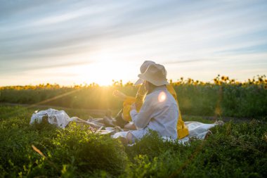İki yakın arkadaş neşeli ve güzel bir açık hava ortamında güneşli bir pikniğin tadını çıkarıyorlar.