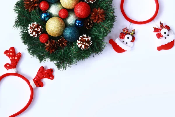 A New Year\'s wreath with Christmas tree bright toys inside on a white background and New Year\'s headbands nearby. Artificial decor for the New Year. Christmas banner or background, screensaver, cover or poster