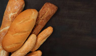 Ekmek masanın üstünde, üst manzara. Uzun somun, baget ve susam tohumlu çörekler.